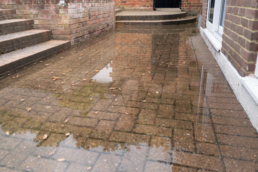 Block paving patio area flooded after heavy rain in Swansea. In need of garden drainage solution by Swansea drainage company