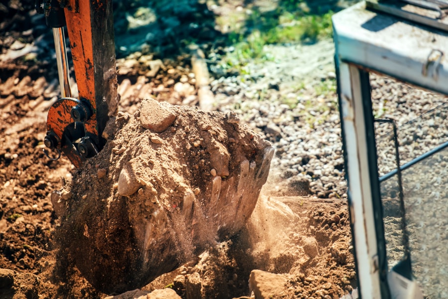 Digger with bucketful of earth and stone while excavating site in Swansea