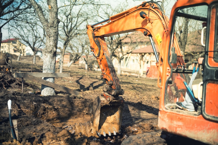 Excavation contractor using orange digger to grade ground on site in Swansea