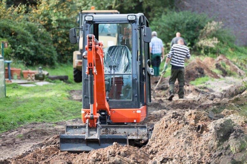 Mini digger stationary and just completed digging out for new drainage pipe in garden