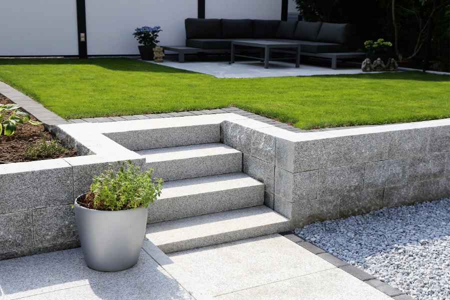 White garden wall with steps leading up to newly laid turfed lawn