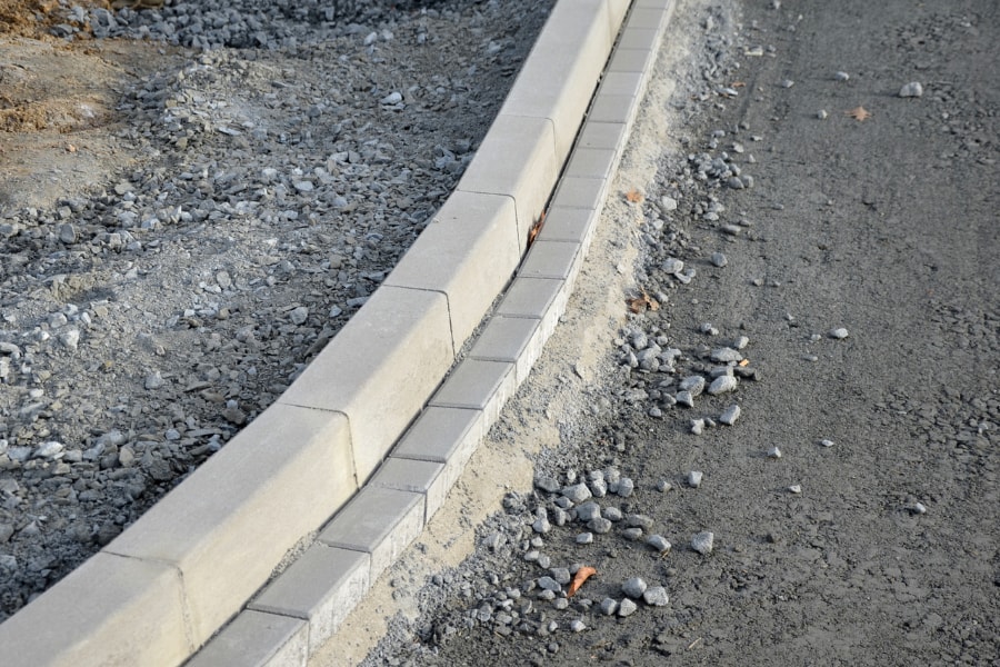 Kerbing stones newly laid on road containing chippings as base coat.